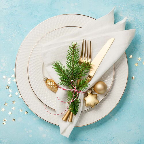 Ein leeres Gedeck mit zwei Tellern mit Besteck und einer Weihnachtsdekoration.