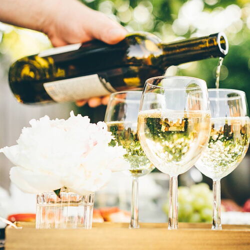 Drei Weingläser auf einem Tisch, die gerade aus einer Flasche gefüllt werden